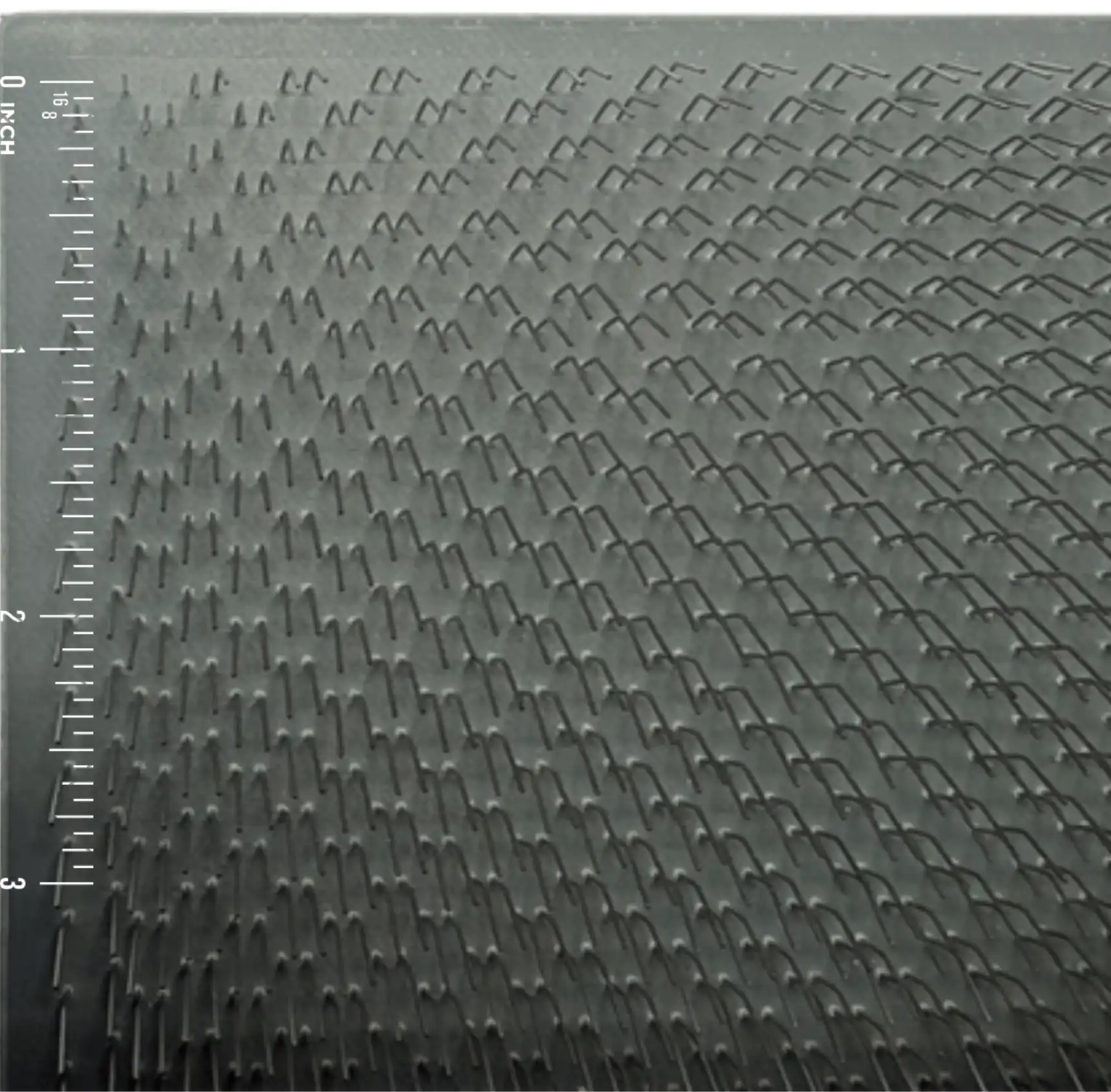 Close-up of 54 TPI carding cloth with an inch scale for size comparison.